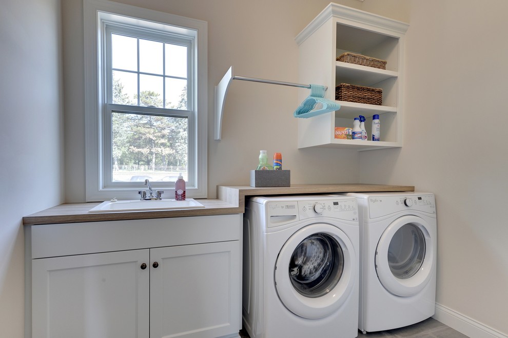 Ejemplo de cuarto de lavado lineal tradicional renovado grande con fregadero encastrado, armarios abiertos, puertas de armario blancas, encimera de laminado, paredes beige y lavadora y secadora juntas