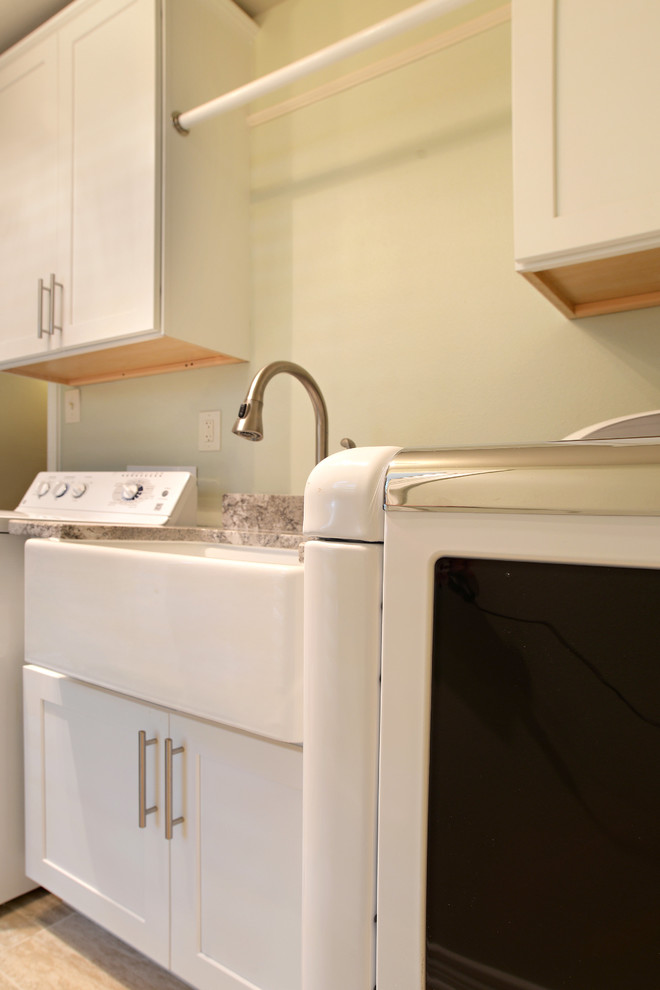 Einzeilige, Mittelgroße Klassische Waschküche mit Schrankfronten im Shaker-Stil, weißen Schränken, Granit-Arbeitsplatte, beiger Wandfarbe, Waschmaschine und Trockner nebeneinander, Landhausspüle und Porzellan-Bodenfliesen in Dallas