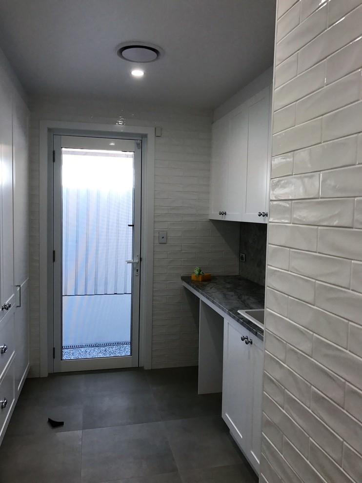 Large classic single-wall separated utility room in Brisbane with a built-in sink, shaker cabinets, white cabinets, engineered stone countertops, white walls, porcelain flooring, a side by side washer and dryer, grey floors and multicoloured worktops.
