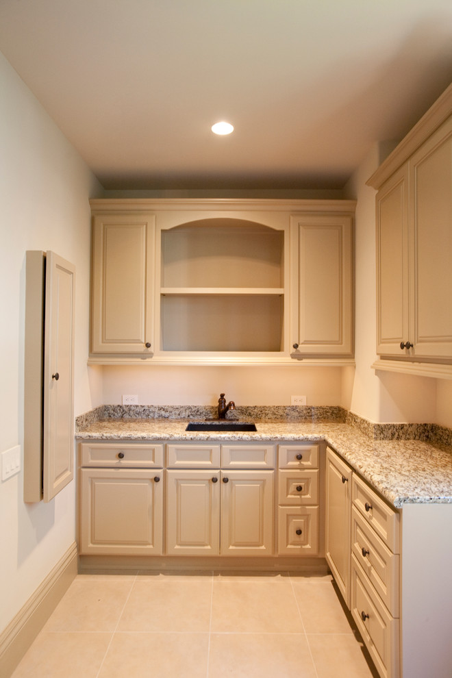Expansive mediterranean l-shaped separated utility room in Houston with a submerged sink, raised-panel cabinets, beige cabinets, granite worktops, beige walls, porcelain flooring and a side by side washer and dryer.