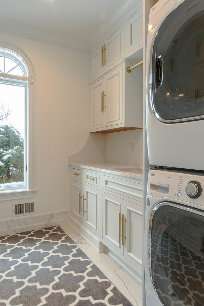 Klassisk inredning av en mellanstor vita linjär vitt tvättstuga enbart för tvätt, med luckor med infälld panel, vita skåp, bänkskiva i kvarts, vita väggar, marmorgolv, en tvättpelare och vitt golv