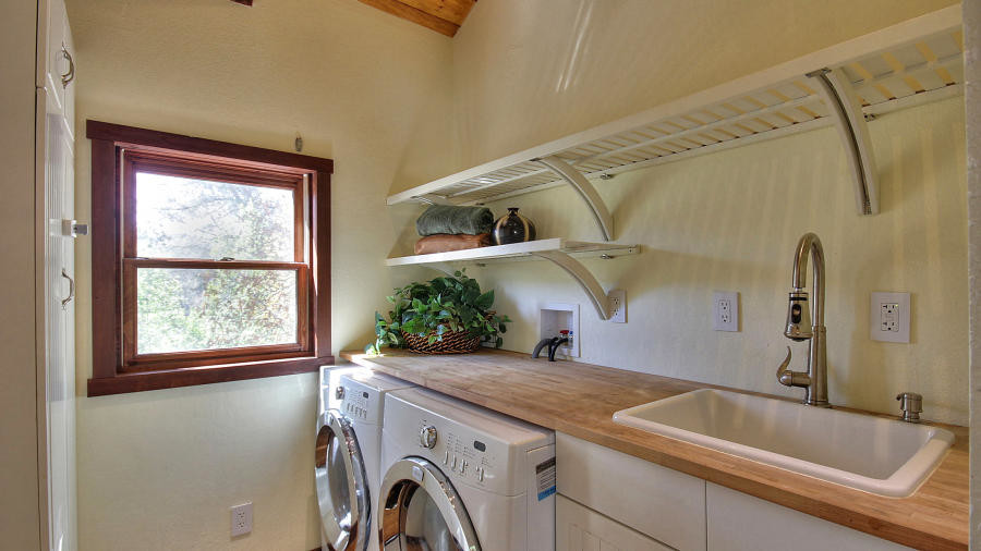 Idéer för små lantliga parallella beige tvättstugor, med träbänkskiva, vita skåp, en tvättmaskin och torktumlare bredvid varandra, luckor med infälld panel, en nedsänkt diskho och beige väggar