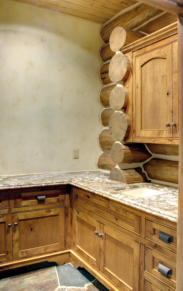 Exempel på en mellanstor rustik l-formad tvättstuga enbart för tvätt, med en undermonterad diskho, luckor med infälld panel, skåp i mellenmörkt trä, granitbänkskiva, beige väggar, skiffergolv och flerfärgat golv