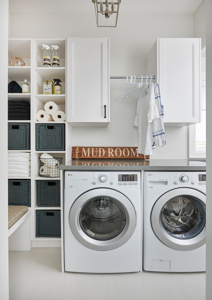Imagen de cuarto de lavado lineal clásico renovado pequeño con armarios con paneles empotrados, puertas de armario blancas, paredes blancas, lavadora y secadora juntas, suelo blanco y encimeras grises