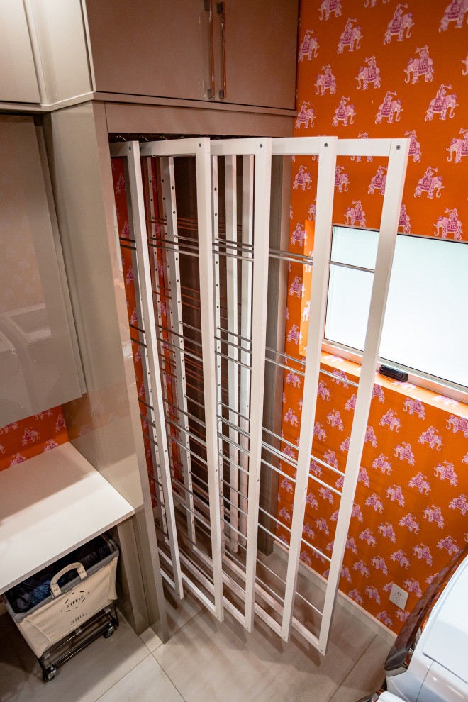 Foto di una grande lavanderia multiuso minimalista con lavello da incasso, ante lisce, ante grigie, top in granito, pareti arancioni, pavimento con piastrelle in ceramica, lavatrice e asciugatrice affiancate, pavimento bianco e top bianco
