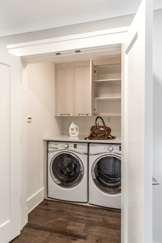 Idee per una sala lavanderia classica di medie dimensioni con ante lisce, ante in legno chiaro, top in laminato, pareti beige, parquet scuro e lavatrice e asciugatrice affiancate
