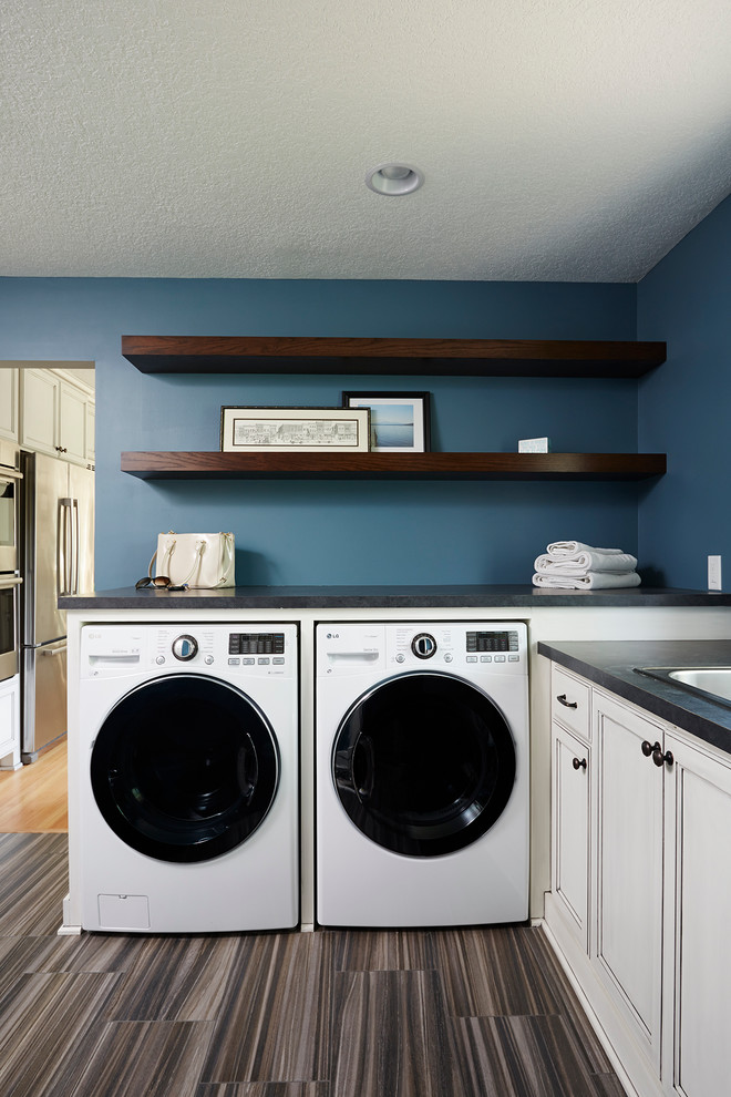 Photo of a large traditional l-shaped utility room in Minneapolis with a built-in sink, recessed-panel cabinets, white cabinets, laminate countertops, blue walls, ceramic flooring, a side by side washer and dryer and brown floors.