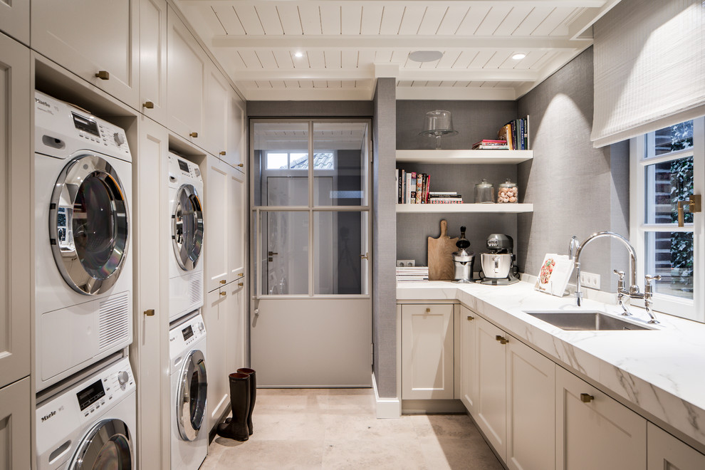 Example of a transitional beige floor utility room design in Amsterdam with an undermount sink, shaker cabinets, white cabinets, gray walls and white countertops