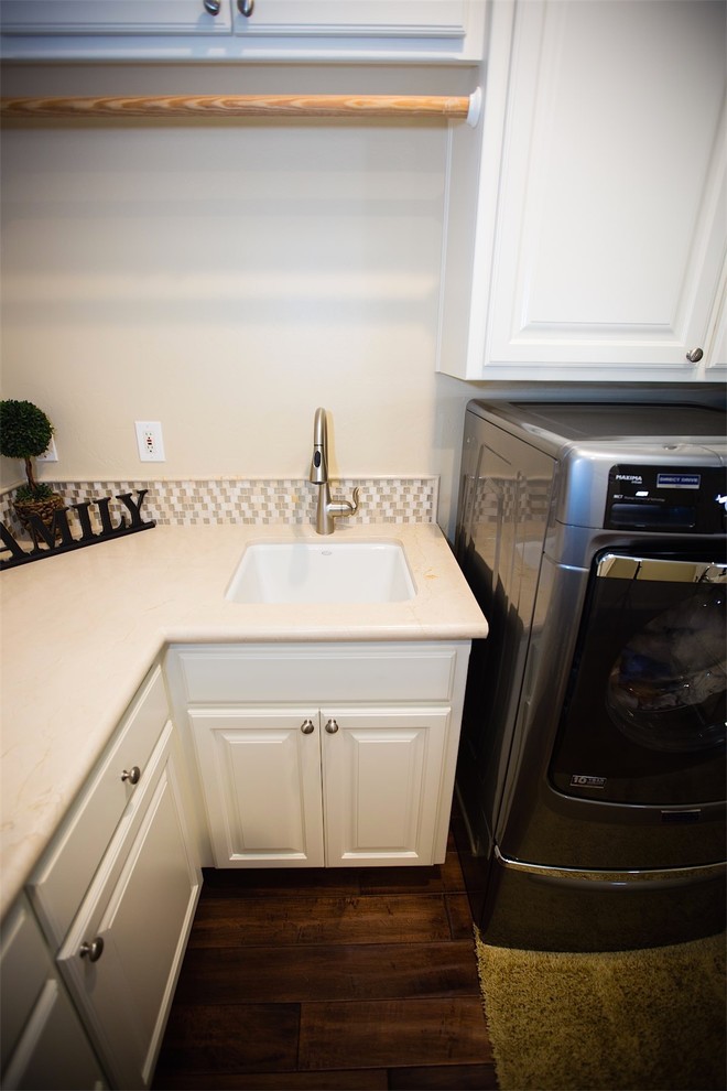 Example of a classic medium tone wood floor laundry room design in Other with an undermount sink, white cabinets, quartz countertops, beige walls and a side-by-side washer/dryer