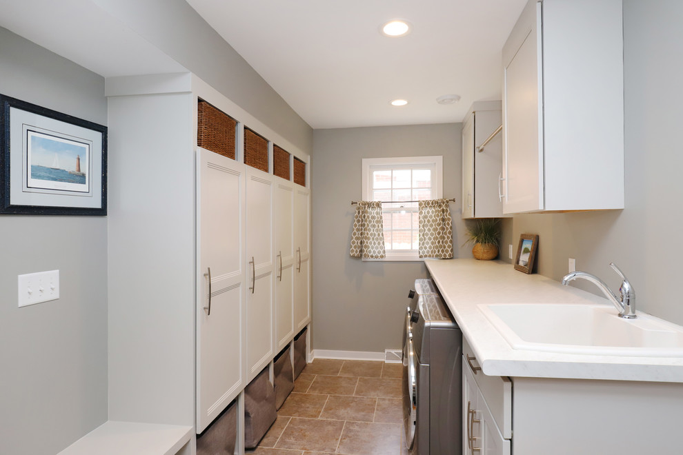 Mid-sized elegant galley laminate floor and brown floor utility room photo in Grand Rapids with shaker cabinets, white cabinets, laminate countertops, gray walls, a side-by-side washer/dryer and a drop-in sink