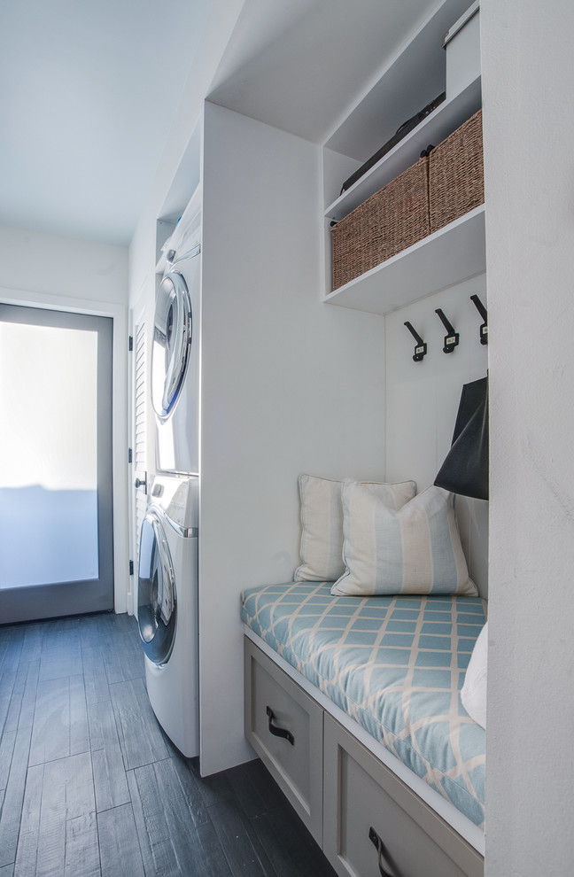 Example of a beach style galley dedicated laundry room design in Los Angeles with a drop-in sink, shaker cabinets, gray cabinets, quartz countertops, white walls and a stacked washer/dryer