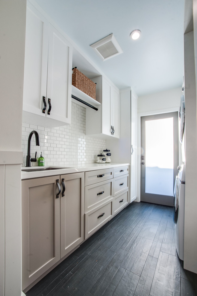 Nautical galley separated utility room in Los Angeles with shaker cabinets, grey cabinets, engineered stone countertops, white walls, a stacked washer and dryer and a submerged sink.