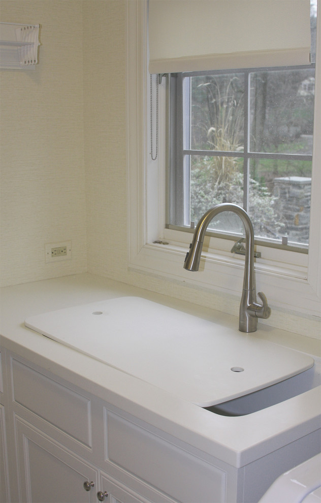 Bild på en mellanstor parallell tvättstuga enbart för tvätt, med en undermonterad diskho, luckor med upphöjd panel, vita skåp, bänkskiva i koppar, gula väggar, mellanmörkt trägolv och en tvättmaskin och torktumlare bredvid varandra