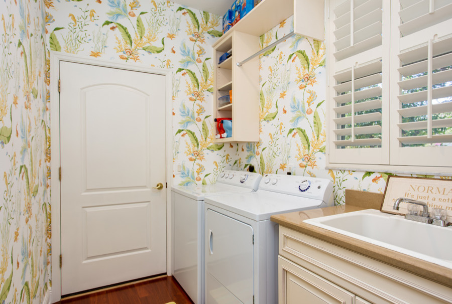 Diseño de cuarto de lavado de galera tropical de tamaño medio con fregadero encastrado, paredes multicolor, suelo de madera en tonos medios y lavadora y secadora juntas