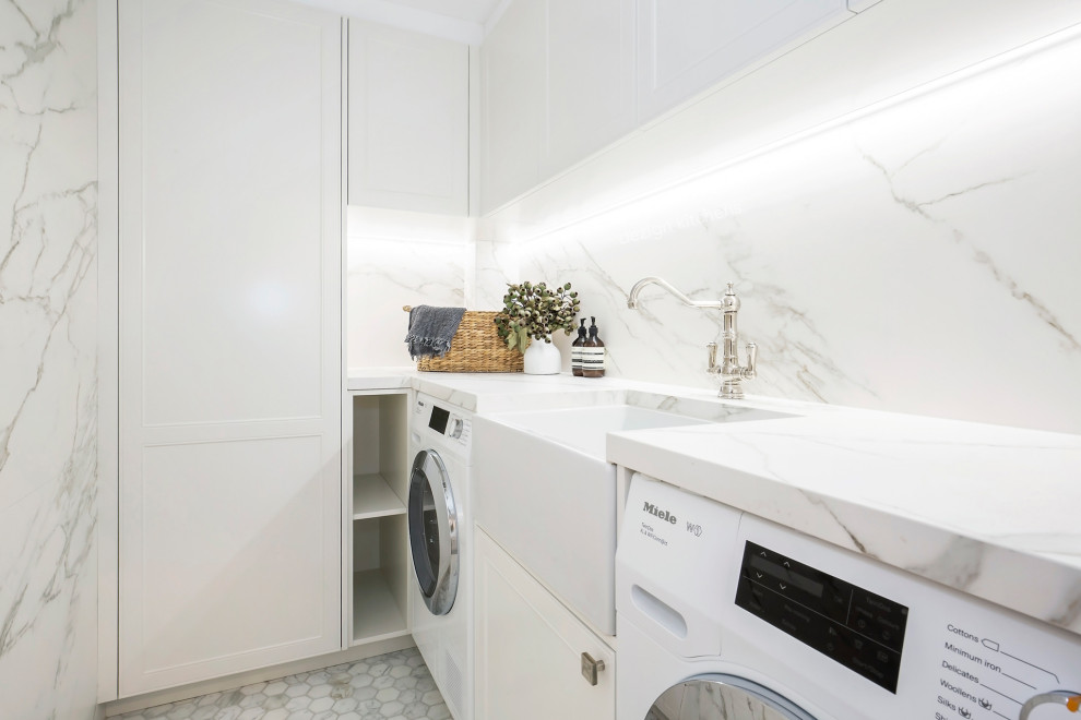 シドニーにある高級な中くらいなトランジショナルスタイルのおしゃれな洗濯室 (L型、エプロンフロントシンク、落し込みパネル扉のキャビネット、白いキャビネット、大理石カウンター、マルチカラーのキッチンパネル、大理石のキッチンパネル、白い壁、無垢フローリング、洗濯乾燥機、白い床、マルチカラーのキッチンカウンター) の写真