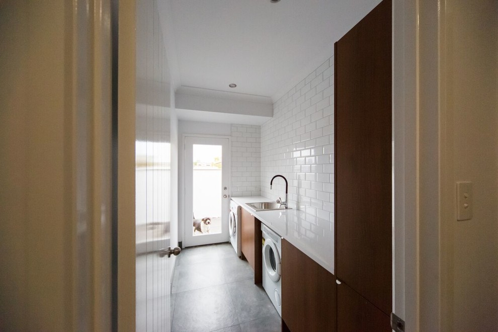 Esempio di una piccola sala lavanderia design con lavello a vasca singola, ante lisce, ante in legno scuro, pareti bianche e lavatrice e asciugatrice affiancate