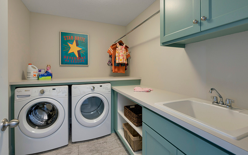 Inspiration for an eclectic l-shaped dedicated laundry room remodel in Minneapolis with a drop-in sink, laminate countertops and a side-by-side washer/dryer