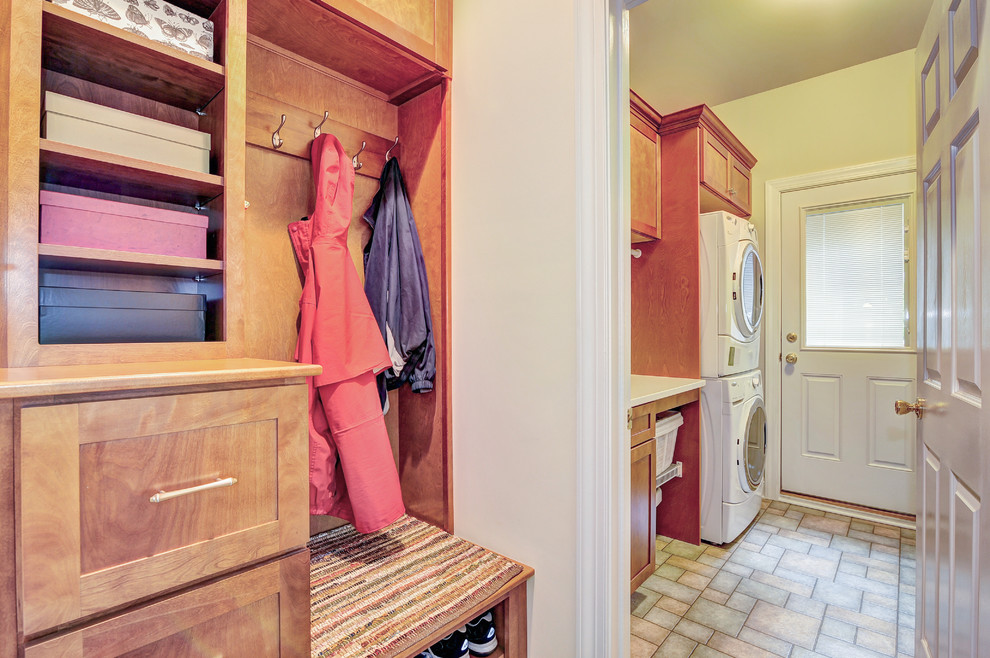 Foto di una piccola lavanderia multiuso chic con ante con riquadro incassato, ante in legno scuro, pavimento con piastrelle in ceramica, lavatrice e asciugatrice a colonna e pareti beige