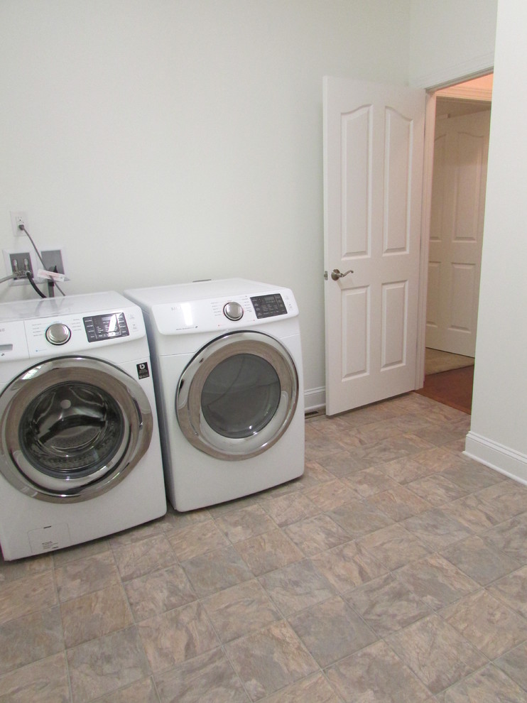 Foto di una grande lavanderia multiuso tradizionale con pareti beige, pavimento in vinile e lavatrice e asciugatrice affiancate