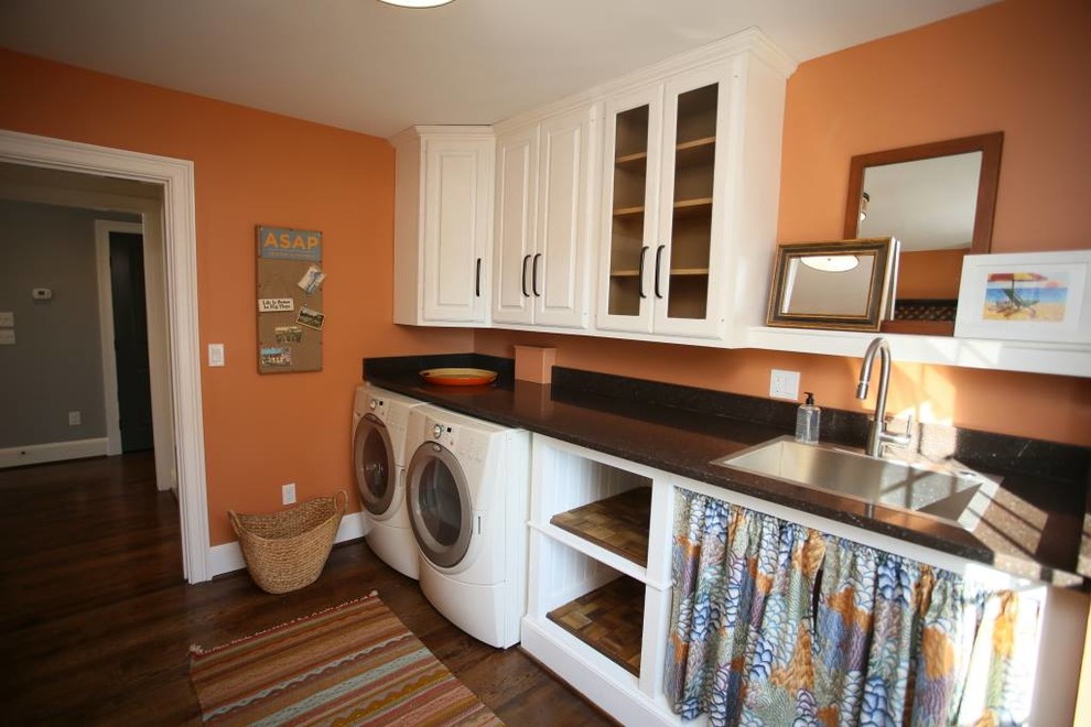 Dedicated laundry room - large transitional single-wall dark wood floor dedicated laundry room idea in Philadelphia with a drop-in sink, raised-panel cabinets, white cabinets, marble countertops, orange walls and a side-by-side washer/dryer
