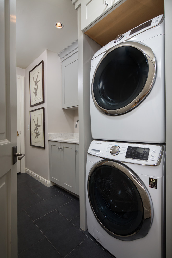 Dedicated laundry room - small coastal single-wall ceramic tile dedicated laundry room idea in Miami with an undermount sink, shaker cabinets, gray cabinets, quartz countertops, gray walls and a stacked washer/dryer