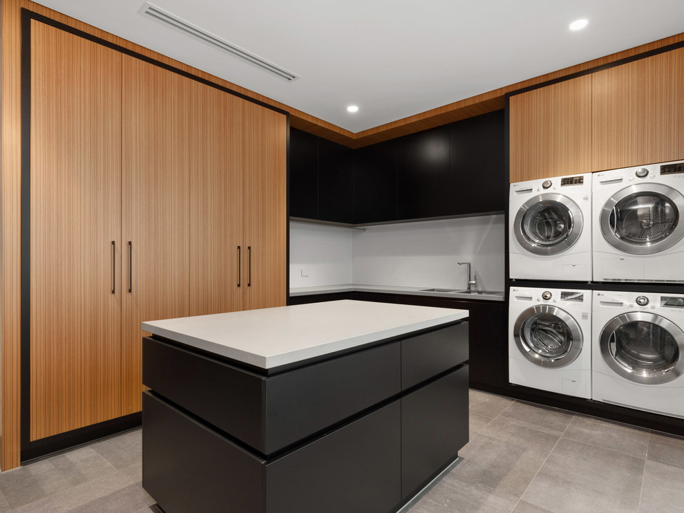 Diseño de lavadero en L contemporáneo con fregadero de doble seno, armarios con paneles lisos, puertas de armario de madera oscura, lavadora y secadora juntas, suelo gris y encimeras blancas