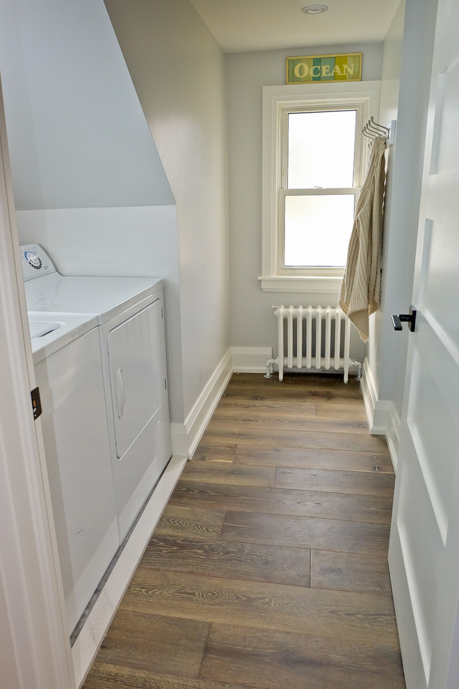 Inspiration for a mid-sized transitional single-wall medium tone wood floor dedicated laundry room remodel in Toronto with white walls and a side-by-side washer/dryer