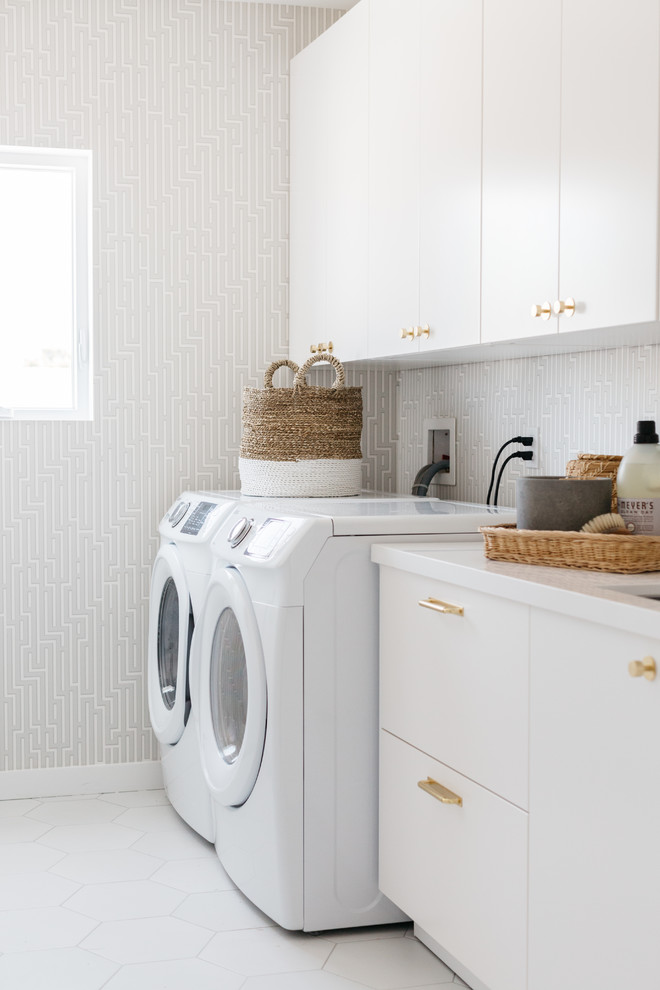 Ispirazione per una lavanderia contemporanea con lavello sottopiano, ante lisce, ante bianche, pareti grigie, lavatrice e asciugatrice affiancate, pavimento bianco e top bianco