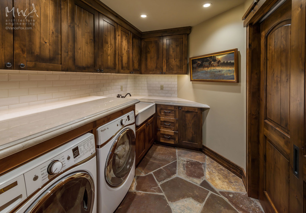 Dedicated laundry room - large craftsman l-shaped slate floor dedicated laundry room idea in Sacramento with a farmhouse sink, shaker cabinets, dark wood cabinets, beige walls and a side-by-side washer/dryer