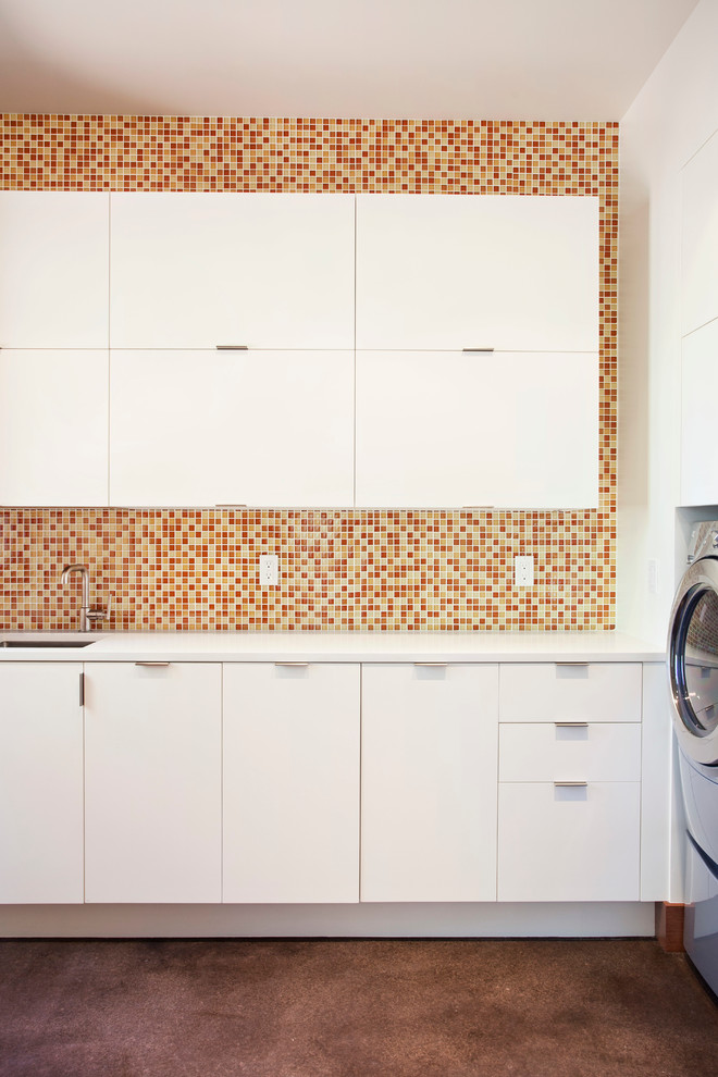 Esempio di una lavanderia minimal con lavello sottopiano, ante lisce, ante bianche, pareti bianche, lavatrice e asciugatrice affiancate, pavimento marrone e top bianco