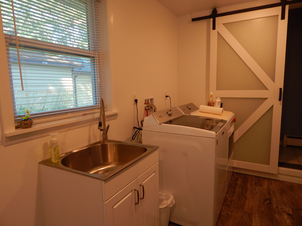 Klassisk inredning av ett mellanstort parallellt grovkök, med vita väggar, laminatgolv, en tvättmaskin och torktumlare bredvid varandra, brunt golv, en nedsänkt diskho, luckor med upphöjd panel och vita skåp