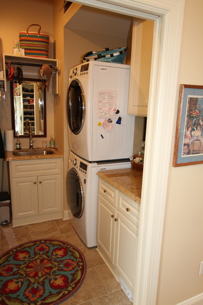 Immagine di una piccola sala lavanderia con ante con bugna sagomata, top in granito, pareti beige, pavimento in terracotta, lavatrice e asciugatrice a colonna e ante beige