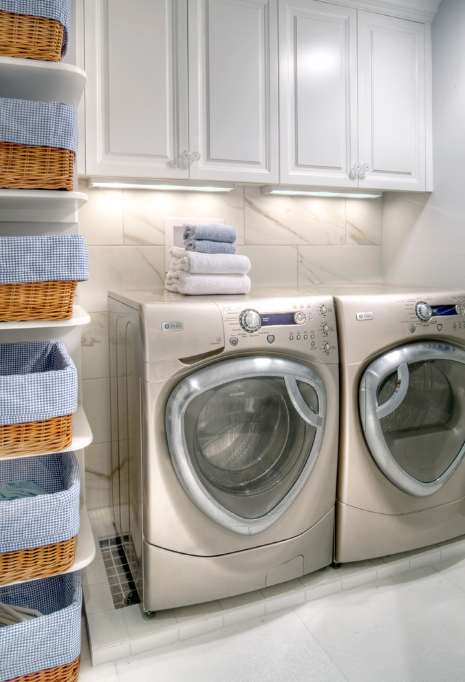 Diseño de lavadero multiusos y en U actual de tamaño medio con puertas de armario blancas, paredes blancas, suelo de baldosas de cerámica y lavadora y secadora juntas