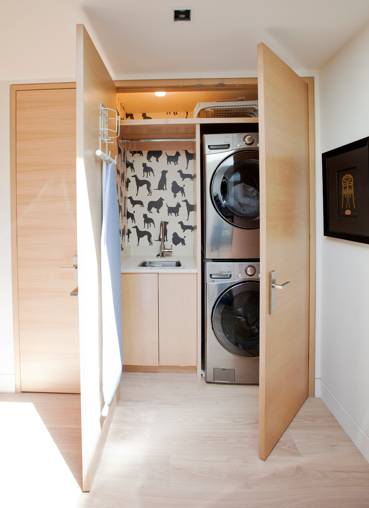 Inspiration for a contemporary single-wall light wood floor and beige floor laundry closet remodel in Vancouver with an undermount sink, flat-panel cabinets, light wood cabinets, white walls, a stacked washer/dryer and white countertops