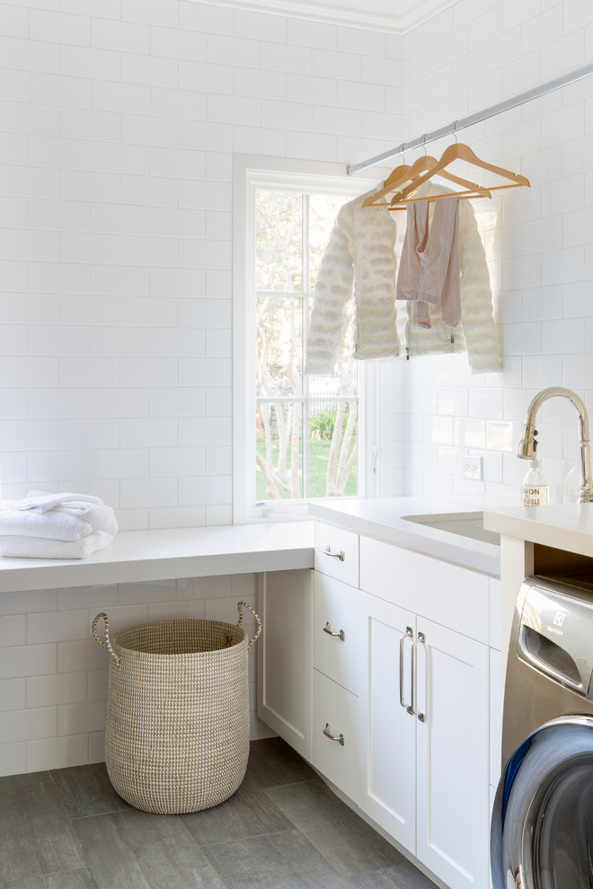 Immagine di una sala lavanderia costiera con lavello sottopiano, ante in stile shaker, ante bianche, pareti bianche, pavimento marrone e top grigio