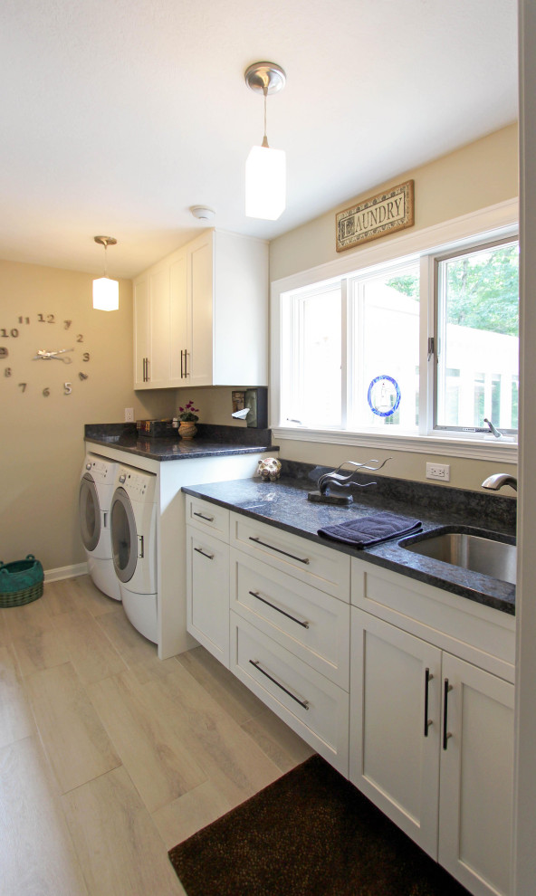 Example of a small transitional single-wall dedicated laundry room design in Cleveland with an undermount sink, recessed-panel cabinets, white cabinets, quartz countertops, a side-by-side washer/dryer and black countertops