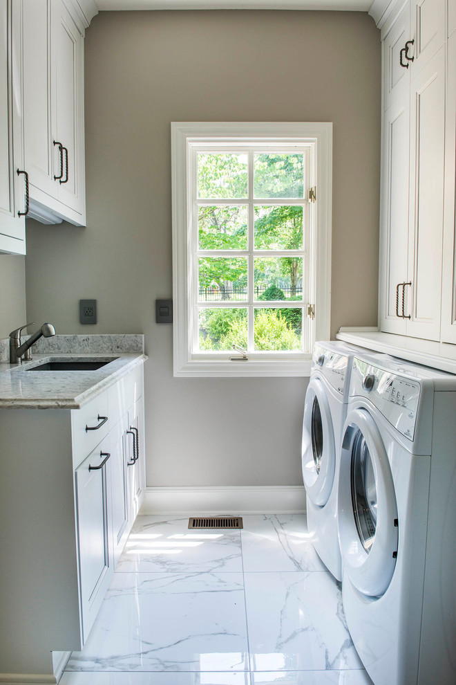 Foto på en liten vintage vita parallell tvättstuga enbart för tvätt, med en undermonterad diskho, luckor med infälld panel, vita skåp, bänkskiva i kvartsit, beige väggar, marmorgolv, en tvättmaskin och torktumlare bredvid varandra och vitt golv