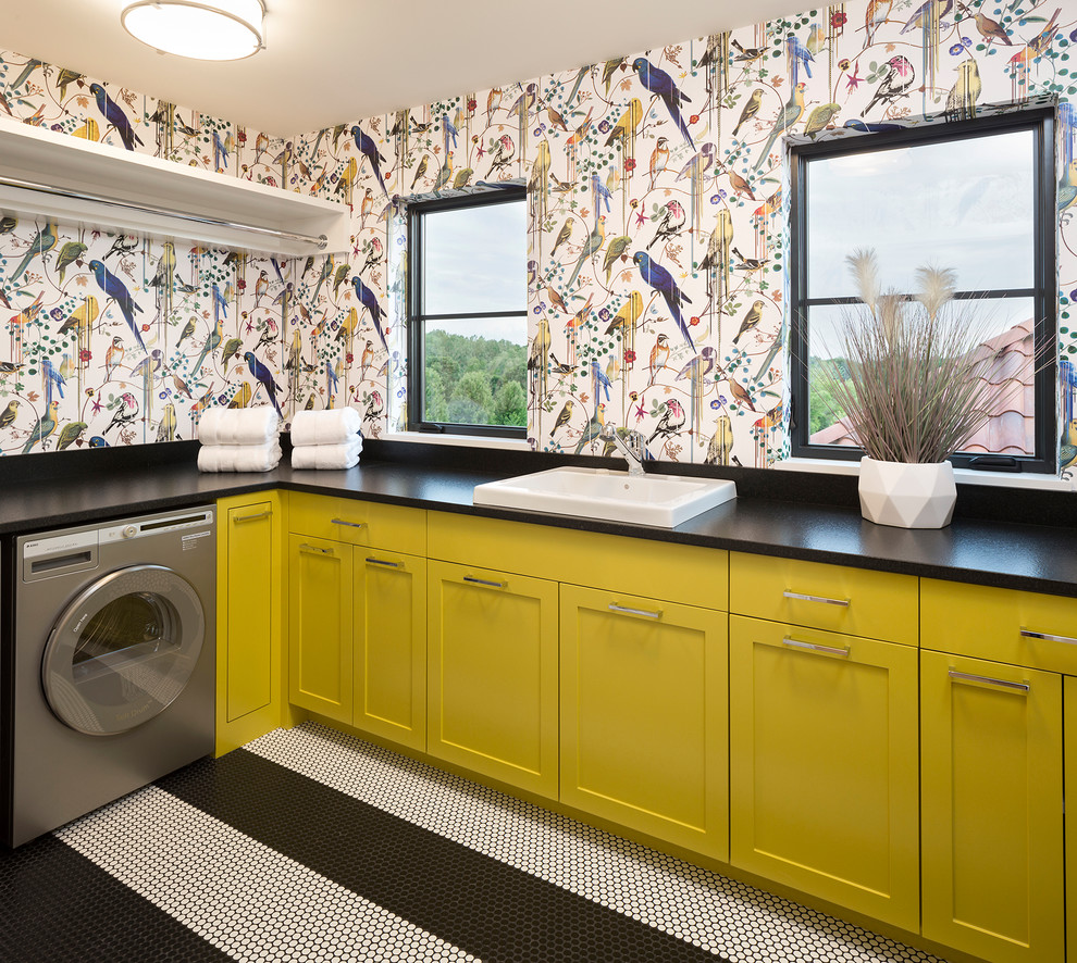 ミネアポリスにある地中海スタイルのおしゃれな洗濯室 (L型、ドロップインシンク、シェーカースタイル扉のキャビネット、黄色いキャビネット、マルチカラーの壁、マルチカラーの床、黒いキッチンカウンター) の写真