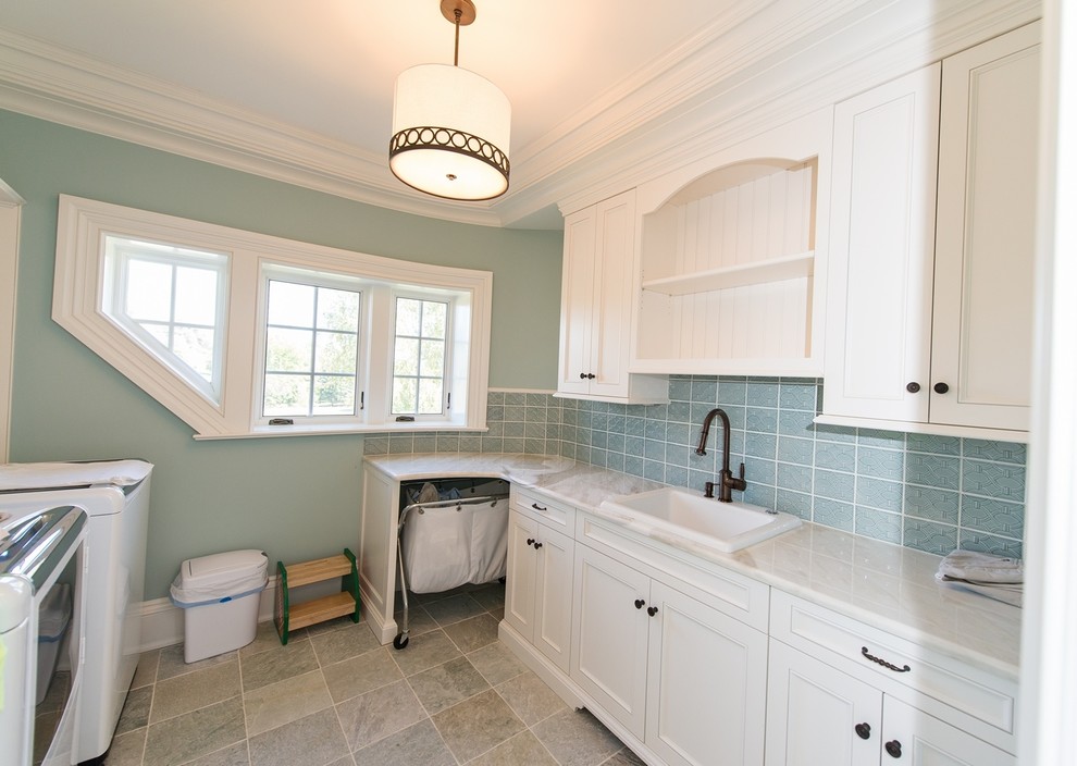 Photo of a large traditional galley utility room in New York with a submerged sink, shaker cabinets, white cabinets, marble worktops, blue walls, porcelain flooring and a side by side washer and dryer.