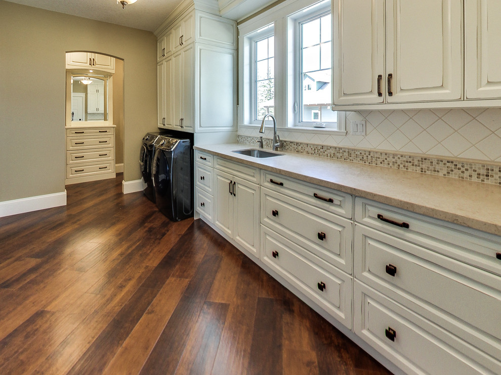 Dedicated laundry room - mid-sized traditional l-shaped medium tone wood floor and brown floor dedicated laundry room idea in Other with an undermount sink, raised-panel cabinets, distressed cabinets, beige walls and a side-by-side washer/dryer