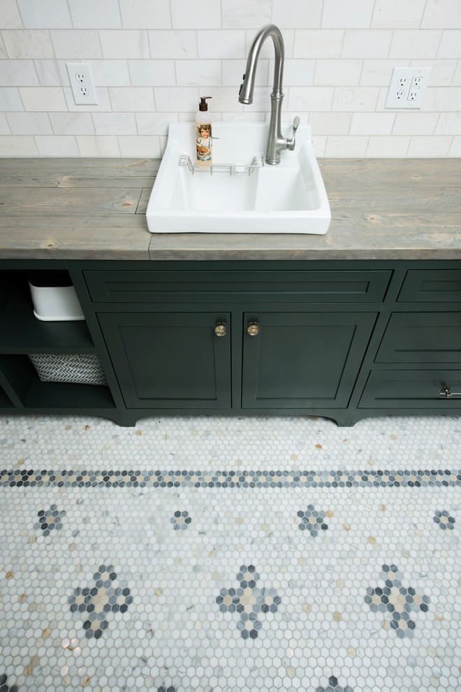 Inredning av en klassisk mellanstor parallell tvättstuga enbart för tvätt, med en nedsänkt diskho, skåp i shakerstil, gröna skåp, träbänkskiva, gröna väggar, marmorgolv, en tvättmaskin och torktumlare bredvid varandra och vitt golv