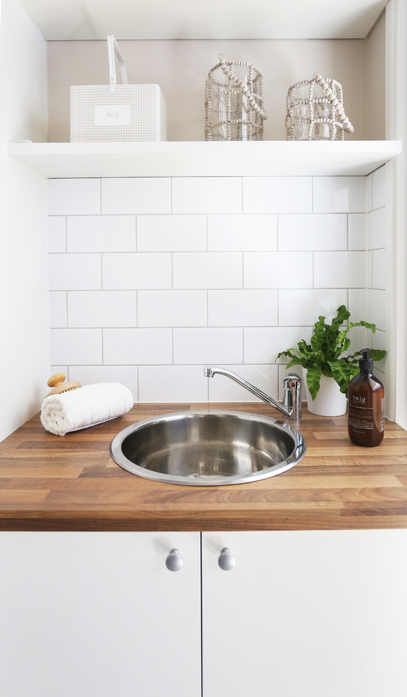 Bild på en liten maritim parallell tvättstuga enbart för tvätt, med släta luckor, vita skåp, laminatbänkskiva, beige väggar, en enkel diskho och klinkergolv i keramik