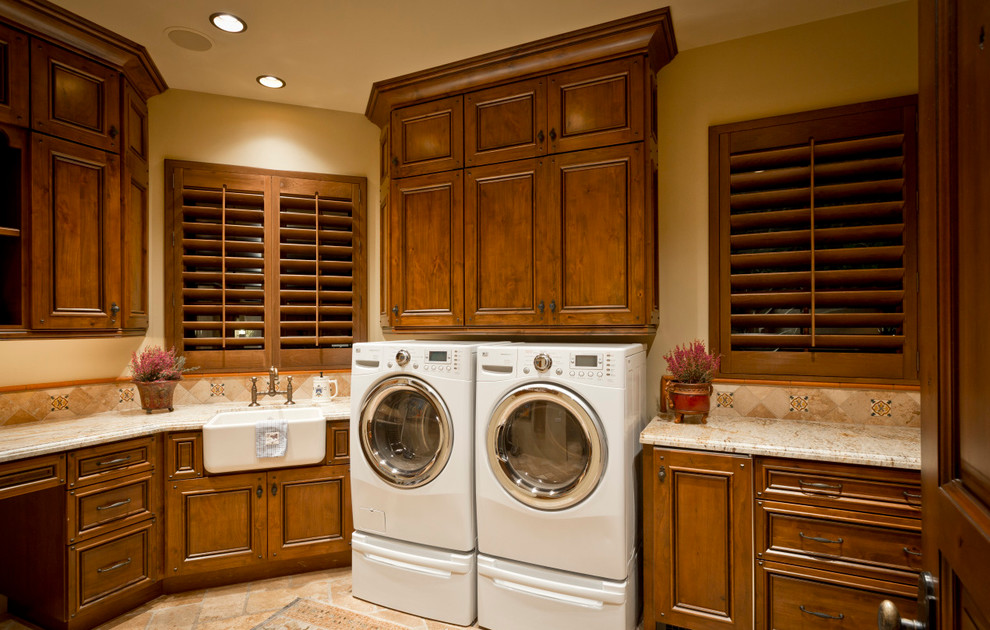 Inspiration for a huge southwestern u-shaped medium tone wood floor dedicated laundry room remodel in Phoenix with granite countertops, beige walls, raised-panel cabinets, dark wood cabinets, a side-by-side washer/dryer and a farmhouse sink