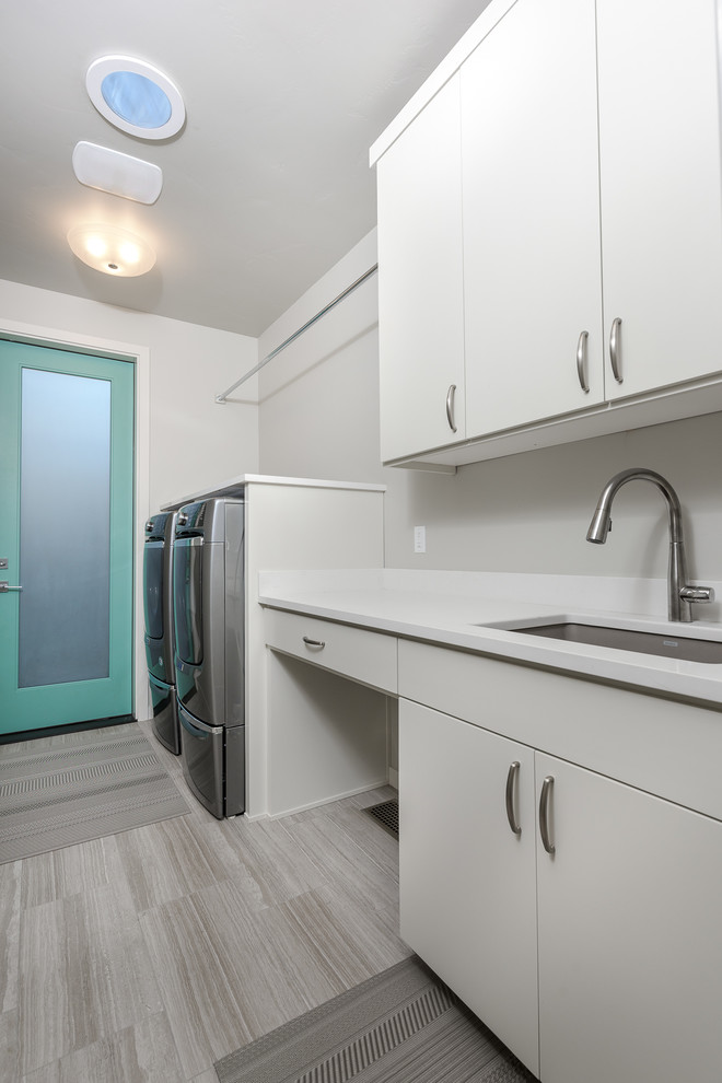 Inspiration for a mid-sized 1960s single-wall porcelain tile and gray floor dedicated laundry room remodel in Portland with an undermount sink, flat-panel cabinets, white cabinets, quartz countertops, white walls, a side-by-side washer/dryer and white countertops