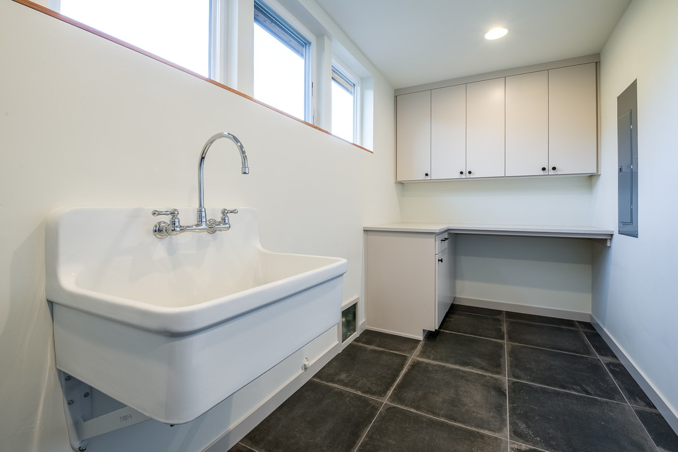 Mid-sized 1960s single-wall porcelain tile and gray floor dedicated laundry room photo in Other with an utility sink, flat-panel cabinets, beige cabinets, white walls and a side-by-side washer/dryer