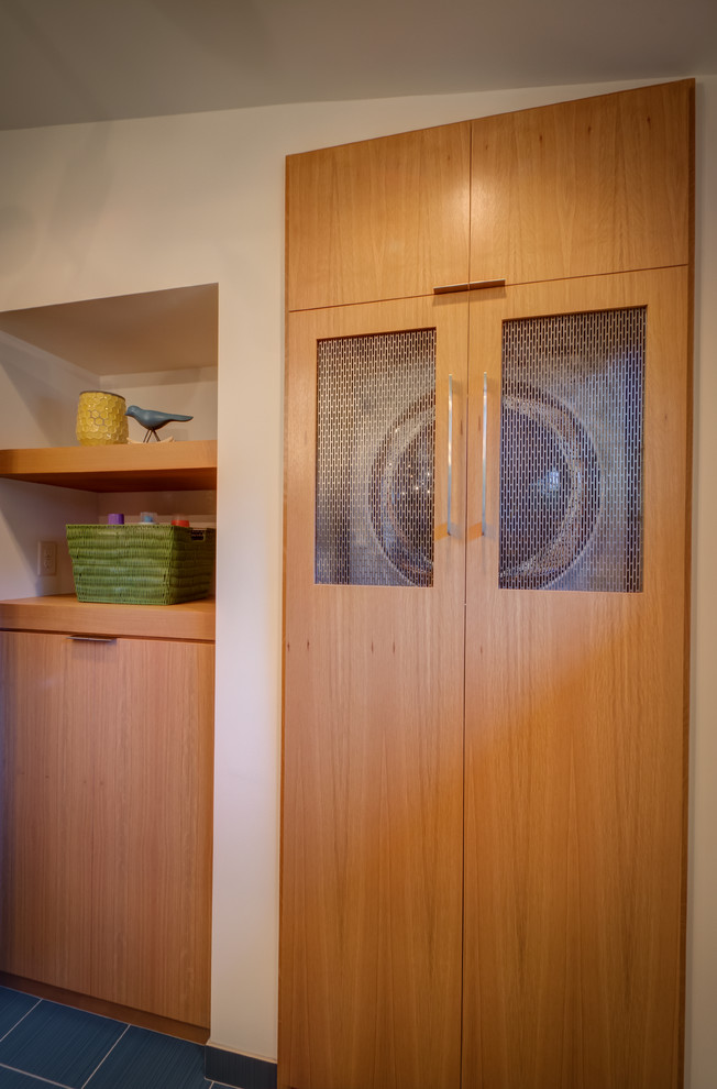 This is an example of a retro laundry cupboard in Minneapolis with flat-panel cabinets, a stacked washer and dryer and medium wood cabinets.