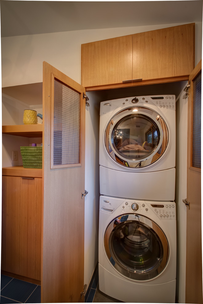 Diseño de armario lavadero vintage con armarios con paneles lisos, lavadora y secadora apiladas y puertas de armario de madera oscura