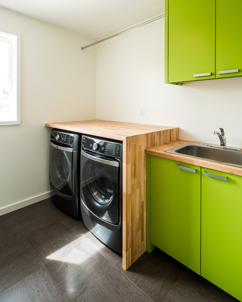 Exempel på en liten 60 tals linjär tvättstuga, med en nedsänkt diskho, släta luckor, gröna skåp, träbänkskiva, vita väggar och en tvättmaskin och torktumlare bredvid varandra