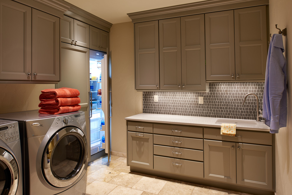 Photo of a large classic l-shaped separated utility room in Denver with a submerged sink, recessed-panel cabinets, grey cabinets, engineered stone countertops, beige walls, limestone flooring and a side by side washer and dryer.