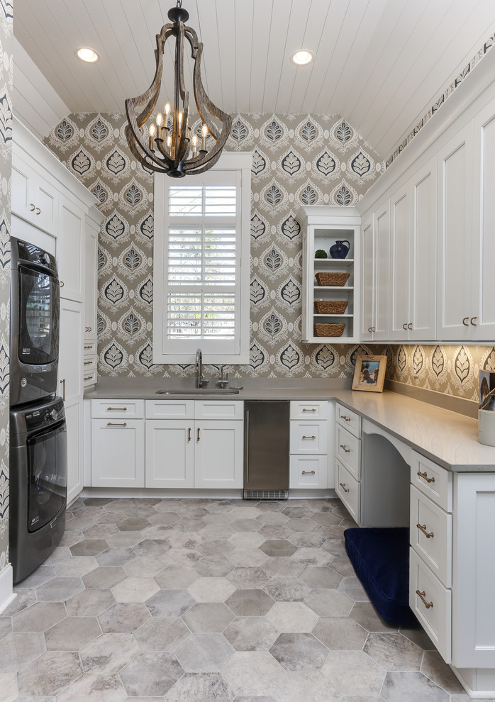 Design ideas for a large traditional u-shaped utility room in Raleigh with a submerged sink, white cabinets, engineered stone countertops, multi-coloured walls, a stacked washer and dryer, grey worktops, shaker cabinets, grey floors and feature lighting.